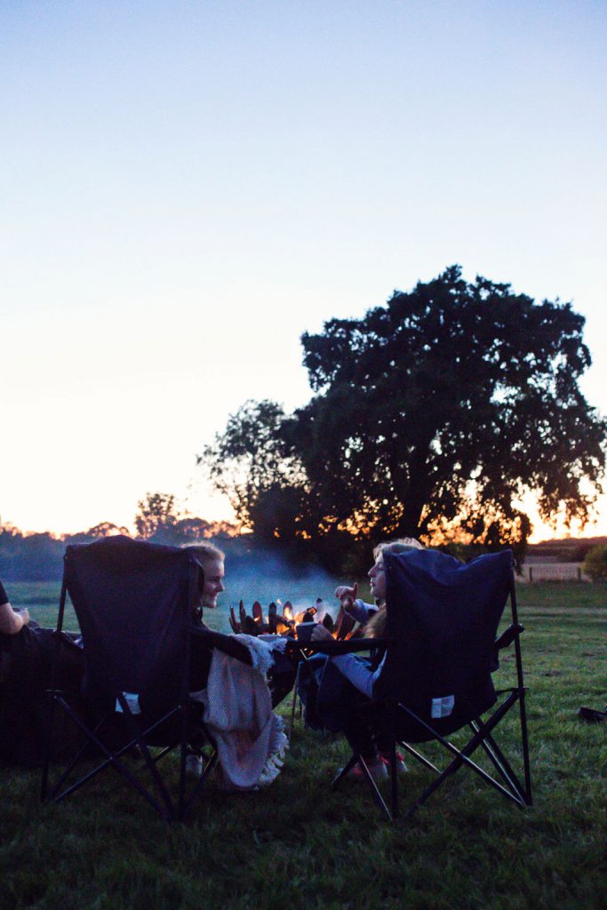 two girls chatting round a fire pit watching the sun set